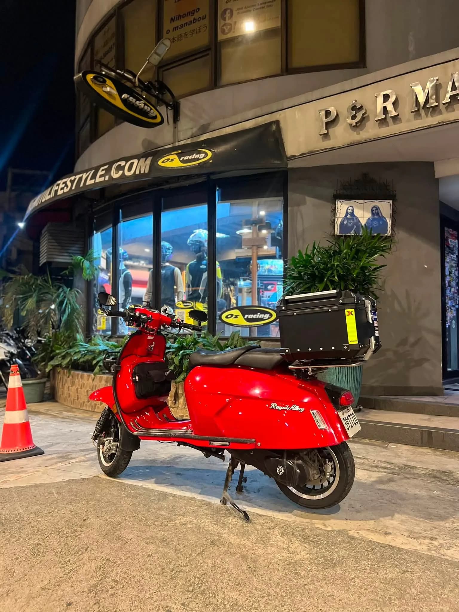 Red Royal Alloy scooter parked outside the Street Pro Culture shop at night